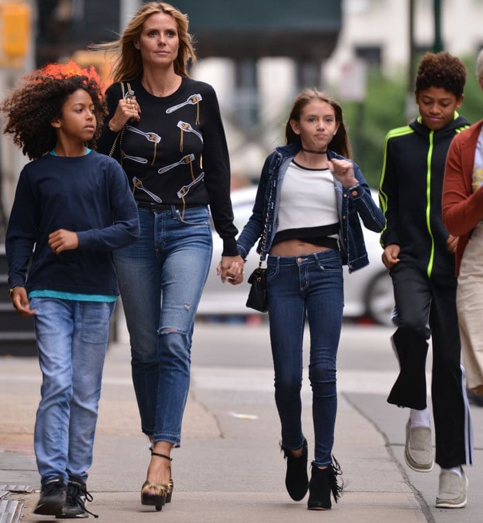 Heidi Klum's daughter, Leni Olumi Klum, wears a stylish yet casual outfit featuring a dark denim jacket over a white crop top, paired with skinny jeans and black ankle boots