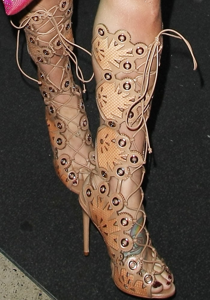Kesha flaunts her pedicured toes in intricate Ivy Kirzhner “Cannes” lace-up gladiator sandals, featuring metallic grommets and cutout sunburst details
