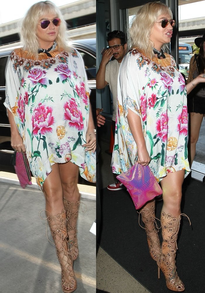 Kesha completed her bold travel look with mirrored Ray-Ban aviators, a black bandana scarf, and beige lace-up gladiator heels that added edge to her floral caftan