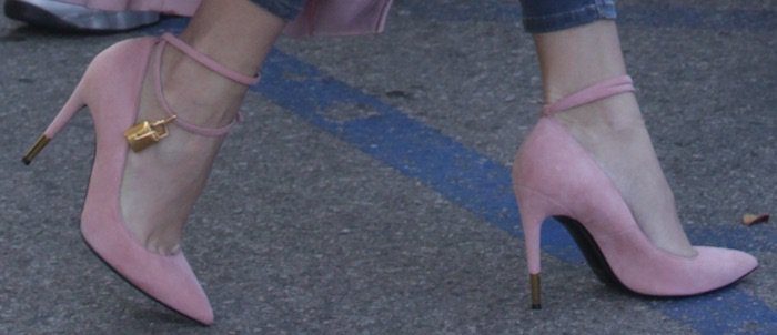 Khloé Kardashian’s pink suede Tom Ford padlock pumps feature slim ankle straps, gold lock charms, and metallic heel tips for a signature statement finish