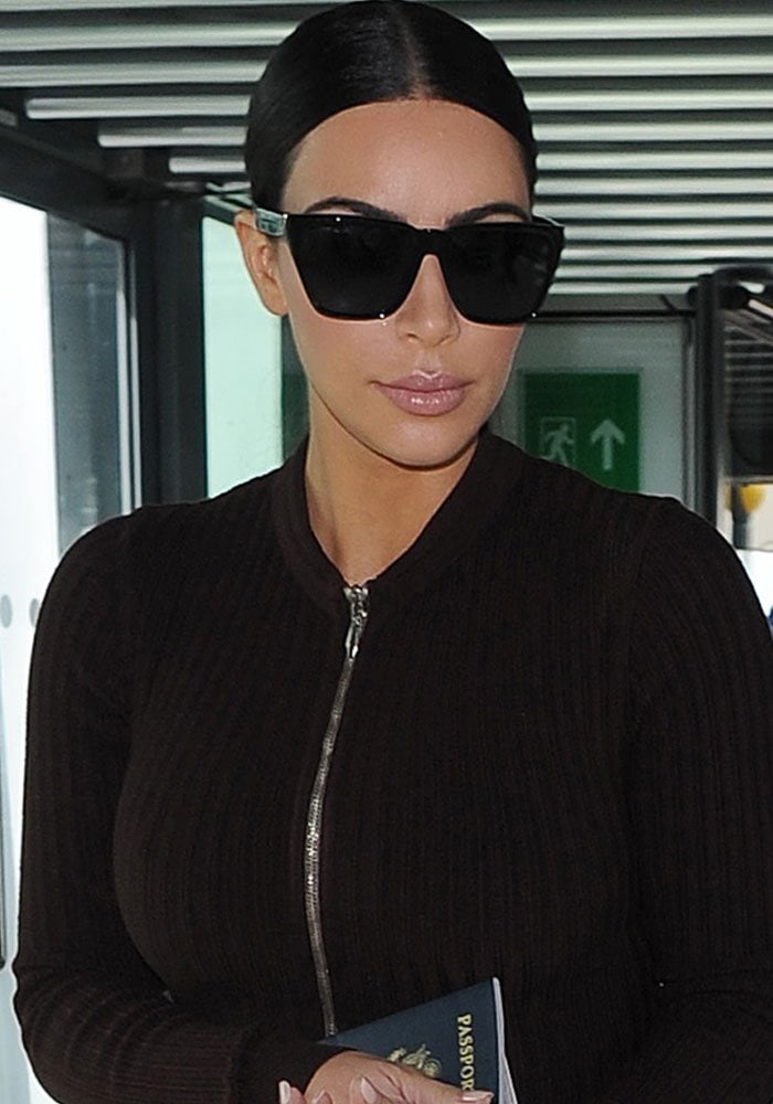 Kim Kardashian keeps her Heathrow beauty look sleek with center-parted hair, glossy nude lips, and oversized black Givenchy sunglasses