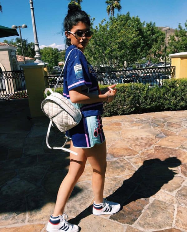 Kylie Jenner embraces playful streetwear vibes in a colorful jersey set and Adidas sneakers, topped off with a white quilted Chanel backpack for a sporty-luxe finish