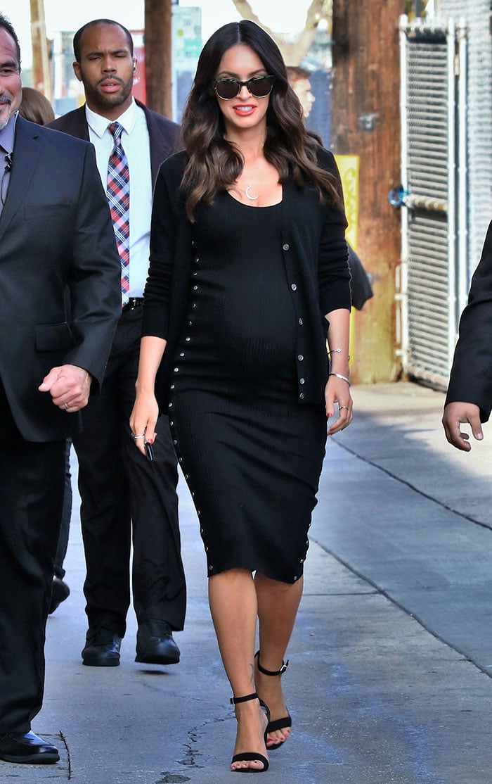 Megan Fox highlighted her baby bump in a sleek, curve-hugging black Alexander Wang dress, styled with minimal ankle-strap heels that added height without distracting from the streamlined silhouette