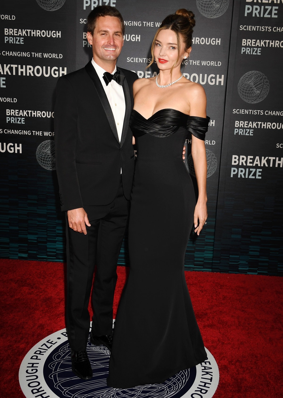 Miranda Kerr stuns in a sleek black off-the-shoulder Zuhair Murad gown paired with Rahaminov Diamonds jewelry as she poses with husband Evan Spiegel at the 9th Annual Breakthrough Prize Ceremony