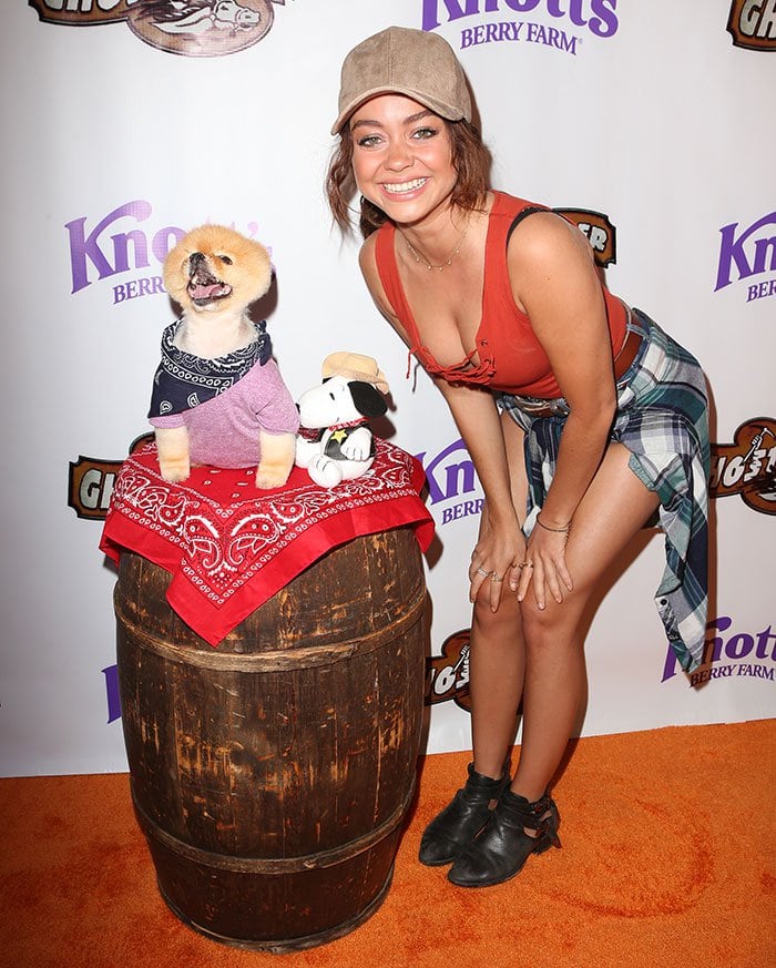 Smiling beside Jiff the Pomeranian, Sarah Hyland keeps her playful cowgirl look grounded with low-heeled ankle boots and effortless styling