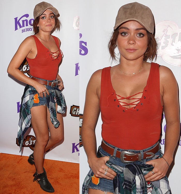 Sarah Hyland balances casual Americana elements with polished details, finishing her look with a suede cap, layered jewelry, and belted denim cutoffs