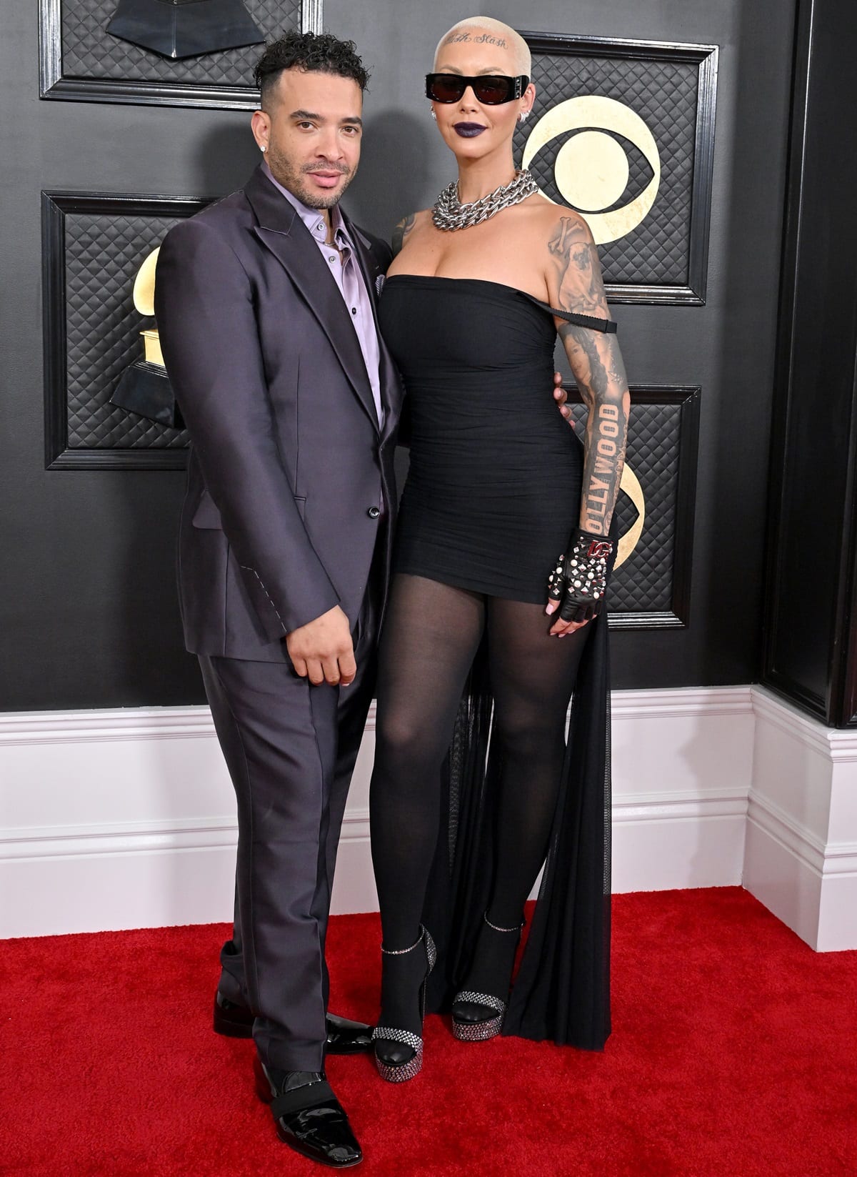 Amber Rose and Jason Lee pose together on the 2023 Grammy Awards red carpet, with Amber commanding attention in a strapless black minidress and platform heels