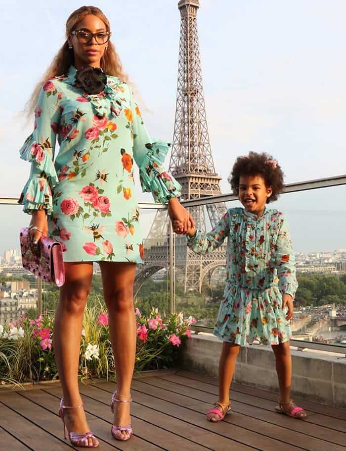 Beyonce and Blue Ivy twinning in vibrant Gucci floral dresses and pink sandals in front of the Eiffel Tower