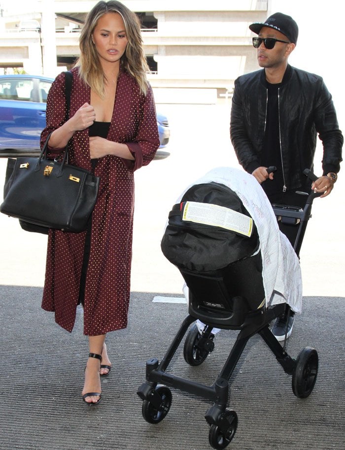 Chrissy Teigen and John Legend wheel their new daughter, Luna Simone Stephens, around LAX for a family vacation
