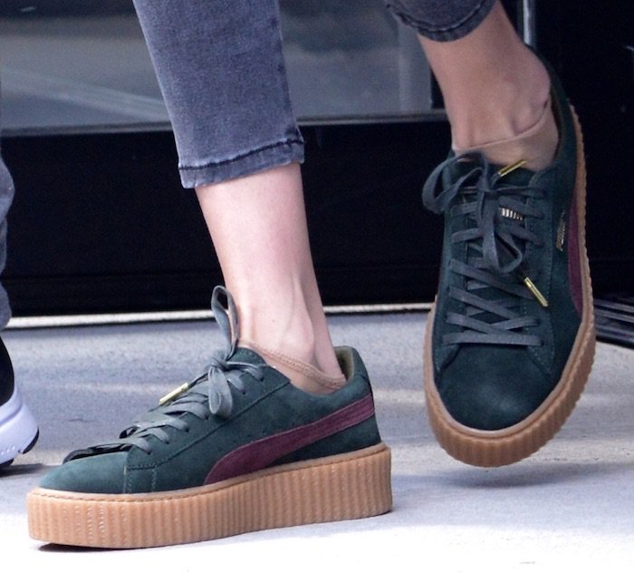 Gigi Hadid steps out in forest-green Puma by Rihanna creepers, pairing the suede platform sneakers with cropped denim to spotlight the ribbed gum sole and Bordeaux Formstrip—an iconic mid-2010s athleisure staple