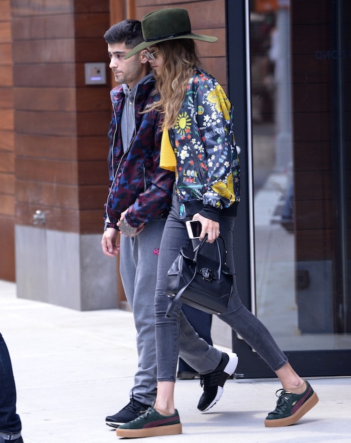 Gigi Hadid accessorizes with a black hat, aviators and a Versace tote bag while walking with Zayn Malik