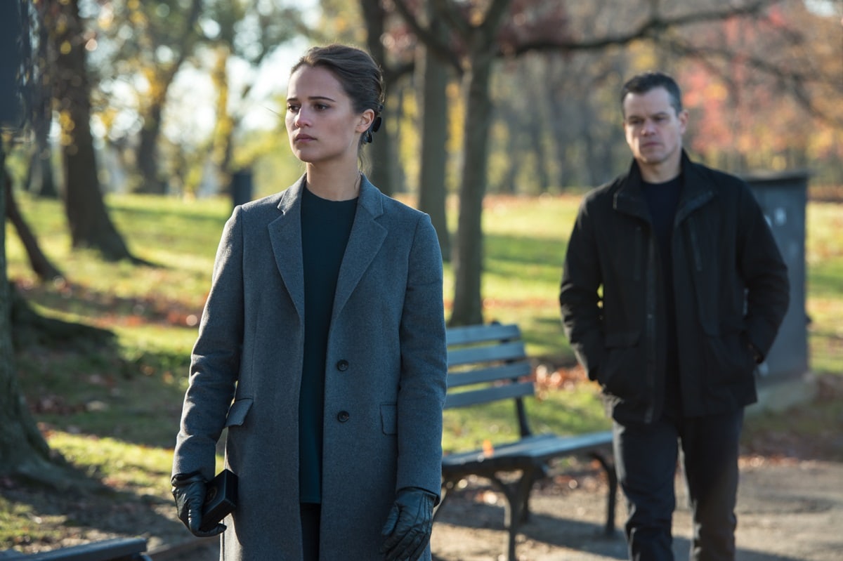 Alicia Vikander brings understated sophistication as CIA cyber specialist Heather Lee in Jason Bourne, pairing a tailored gray coat with sleek leather gloves, while Matt Damon reprises his role as the ever-elusive Jason Bourne