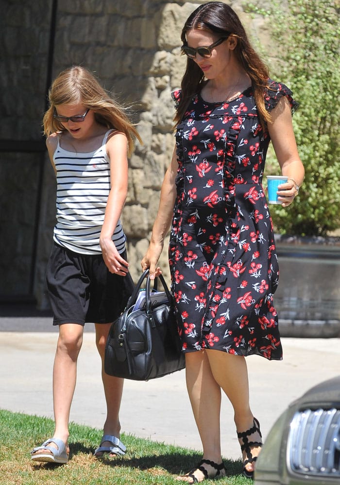 Jennifer Garner steps out in a black floral midi dress paired with Alaïa laser-cut flat sandals as she leaves a church service with her daughter Violet Affleck, who keeps it casual in a striped tank, black shorts, and slide sandals