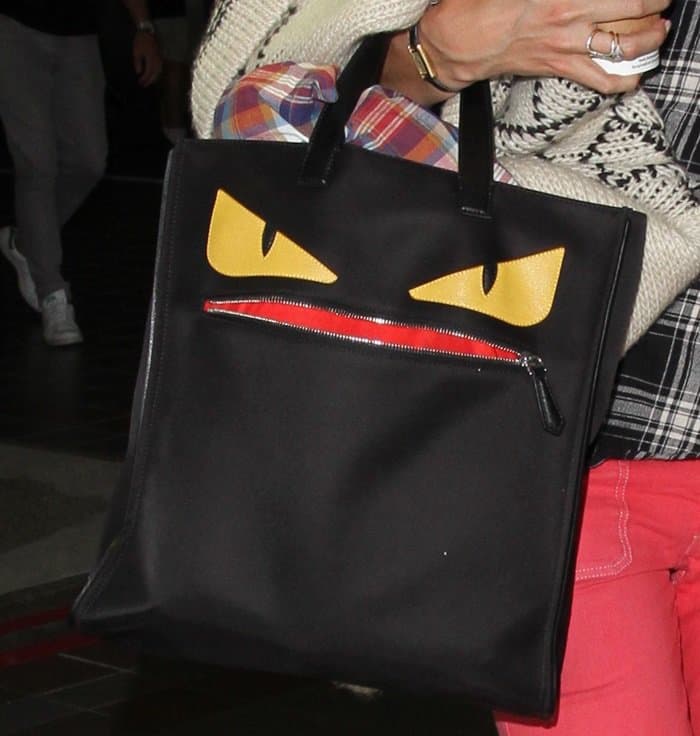 Katie Holmes carried the eye-catching Fendi ‘Monster Creature’ tote, featuring a black structured silhouette with bold yellow monster eyes, a red zippered “mouth” detail, and dual top handles