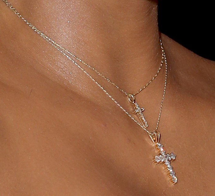 Kim Kardashian elegantly layers two diamond cross necklaces, adding a touch of sparkle to her minimalist ensemble