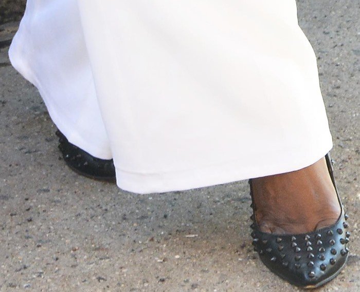 Laverne Cox pairs her white Ramy Brook pants with edgy black studded pumps, adding a bold touch to her chic ensemble