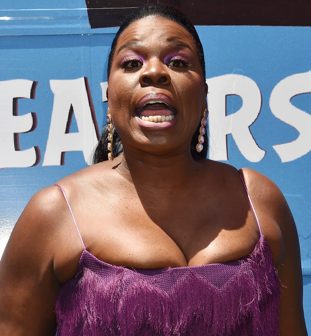 Leslie Jones brings her signature confidence and vibrant energy to the Los Angeles premiere of “The Angry Birds Movie 2,” wearing a bold purple Lia Stublla fringe dress paired with radiant makeup and statement drop earrings