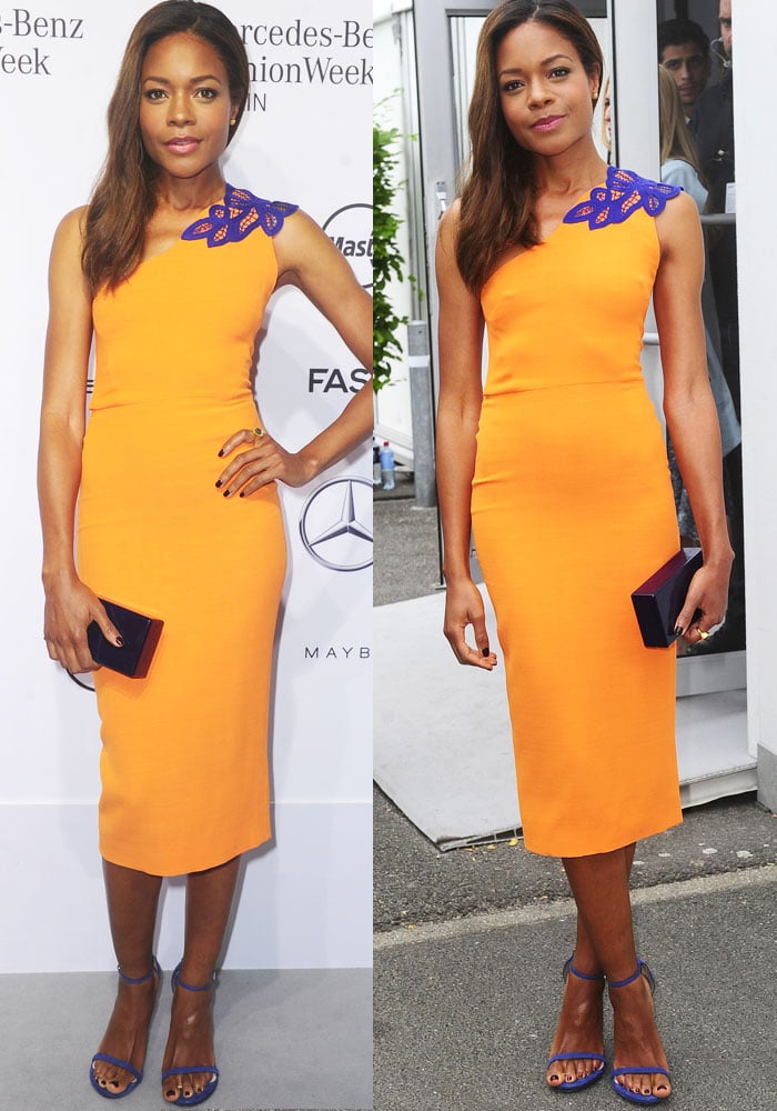 Naomie Harris balances bold color with precision, pairing a fitted orange sheath dress with cobalt accents and minimalist heels for a striking, modern silhouette