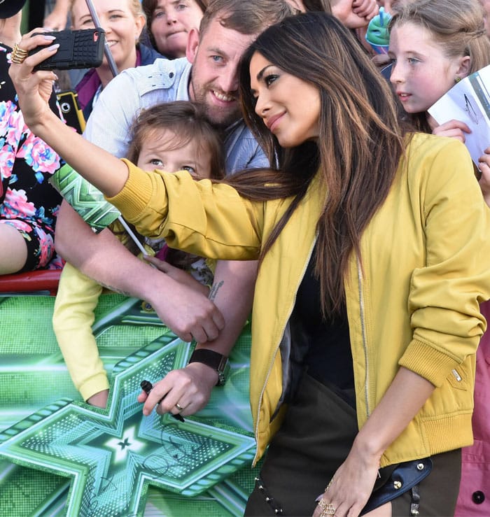 Nicole Scherzinger takes a selfie with fans outside The X Factor Dublin auditions, flashing her signature charm in a mustard yellow jacket and studded Anthony Vaccarello mini skirt