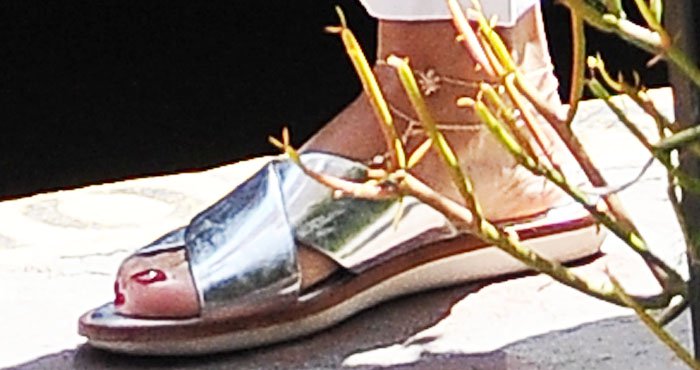 A close-up reveals Vanessa’s mirrored metallic slides, their high-shine finish adding a luxe edge to her relaxed summer outfit
