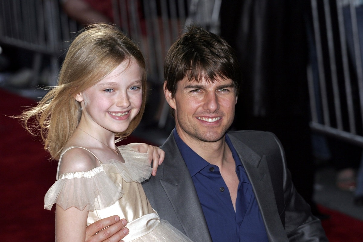 Dakota Fanning looked angelic in a cream off-shoulder tulle dress while posing with Tom Cruise, who wore a sleek navy shirt and gray blazer, as they celebrated their close bond formed during War of the Worlds