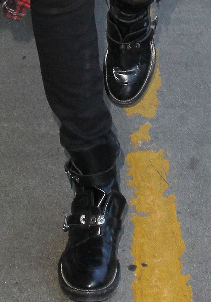 Bella Hadid steps through LAX in her signature Balenciaga “Ceinture” cutout boots, featuring buckled straps, glossy leather, and the style’s iconic metal hardware