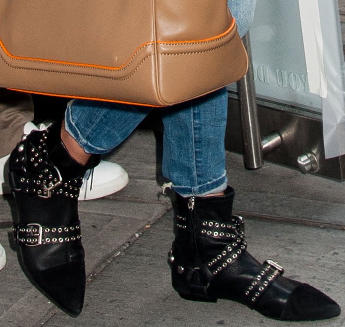 Gigi Hadid steps out in edgy Isabel Marant eyelet-embellished boots featuring bold buckled straps and suede cap toes, perfectly complementing her chic distressed denim