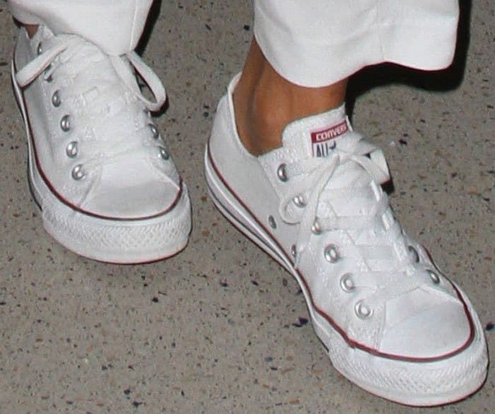 Jessica Alba keeps her airport look effortlessly casual with classic white Converse Chuck Taylor low-top sneakers, a timeless canvas style that has defined off-duty cool for generations