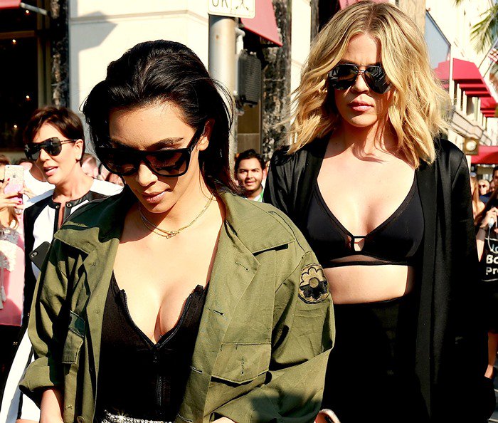 Kim Kardashian pairs an olive green utility shirt with oversized black sunglasses while filming alongside Khloé Kardashian and Kris Jenner on Rodeo Drive