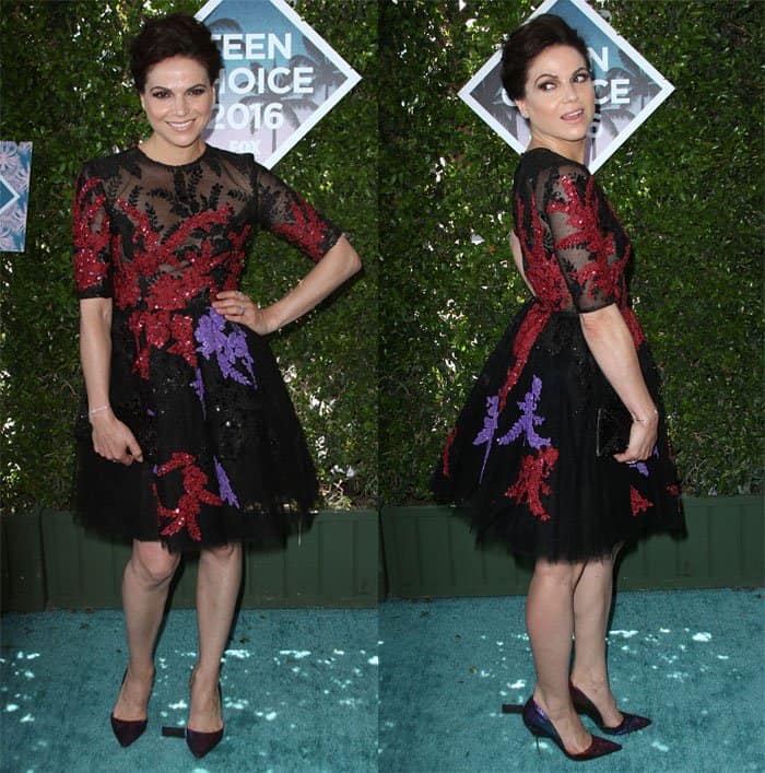 Lana Parrilla delivers a richly textured red-carpet moment at the 2016 Teen Choice Awards, pairing her black Georges Hobeika embroidered tulle dress—layered with red and violet floral appliqués—with pointed-toe burgundy pumps that subtly echo the gown’s palette while elongating her silhouette