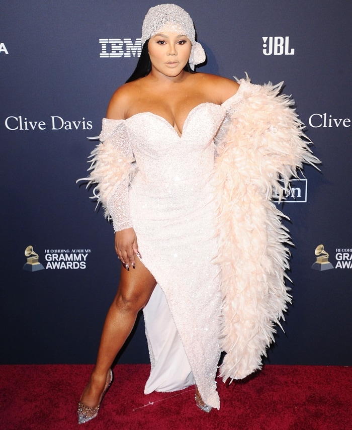 Lil’ Kim stuns on the red carpet at the Pre-GRAMMY Gala honoring Sean “Diddy” Combs at The Beverly Hilton Hotel, wearing a shimmering off-the-shoulder gown with a feathered shawl and sparkling pointed-toe pumps