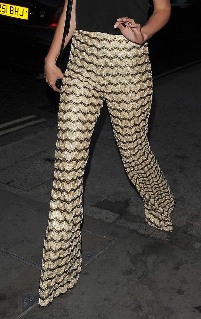 Mollie King stuns in PrettyLittleThing's gold metallic jacquard flare trousers, with her barely visible sandals peeking out beneath the statement-making flares