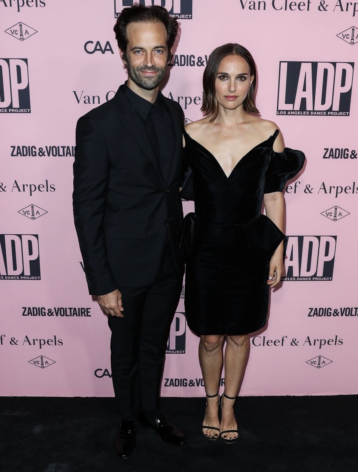 Natalie Portman brings sculptural elegance to the “Unforgettable Evening Under the Stars” in a vintage 1981 Mugler “Vampire” dress, styled with minimalist black ankle-strap sandals that lengthen her silhouette, alongside her husband Benjamin Millepied in a sharply tailored all-black suit