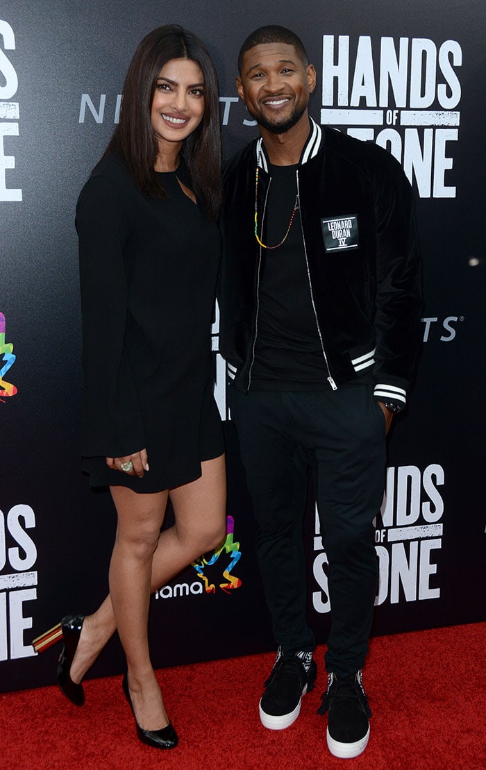 Usher Raymond keeps it casual in a black varsity-style jacket, slim trousers, and black high-top sneakers while attending the Hands of Stone premiere in New York City