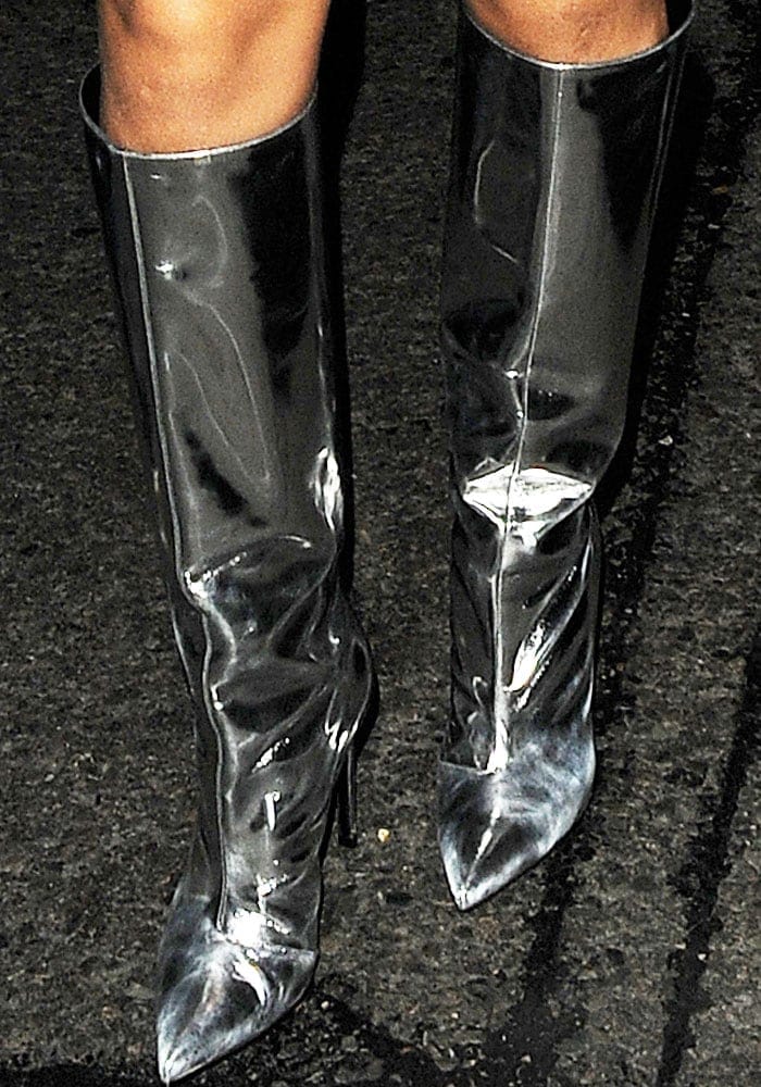 Rihanna completed her denim-heavy nightlife look with Balenciaga’s mirrored leather knee boots, featuring razor-sharp pointed toes, slouchy shafts, and a reflective chrome finish that gave the outfit a futuristic edge