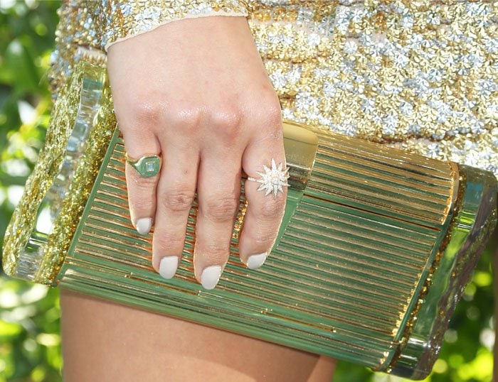 A gold ribbed clutch and statement rings add texture and sparkle, perfectly complementing the shimmering sequin ensemble
