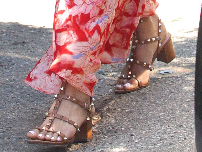 Shay Mitchell steps out in tan leather Valentino “Rockstud” sandals, the signature pyramid studs and stacked block heel lending a grounded, polished edge to her flowing floral dress