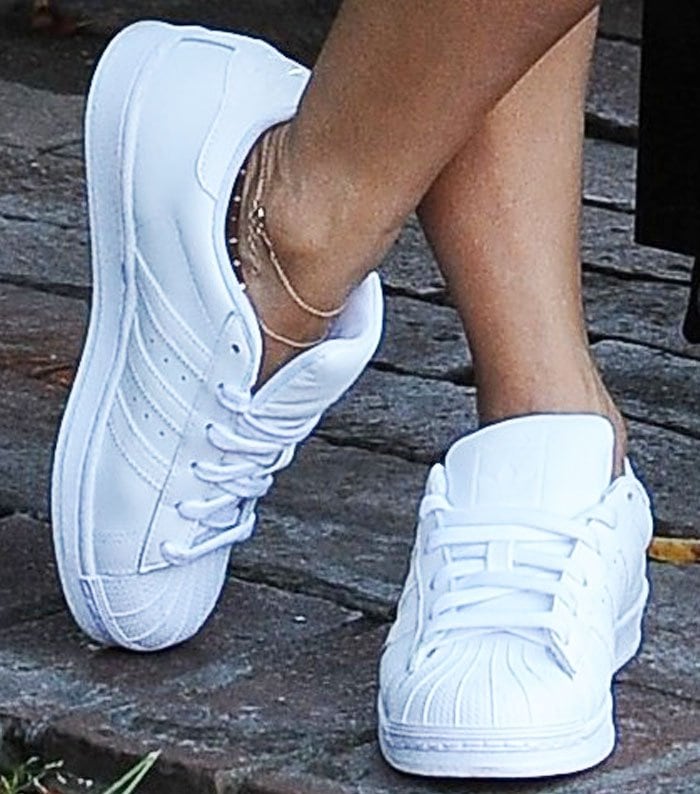 Vanessa Hudgens wears classic white Adidas Superstar sneakers, complemented by a delicate gold anklet