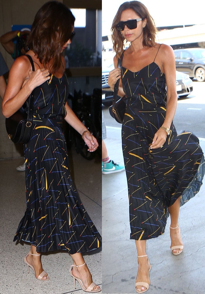 Victoria Beckham elevates her airport style in a pleated midi dress featuring a bold matchstick print and poppy-toned palette, paired flawlessly with nude Manolo Blahnik 'Chaos' sandals