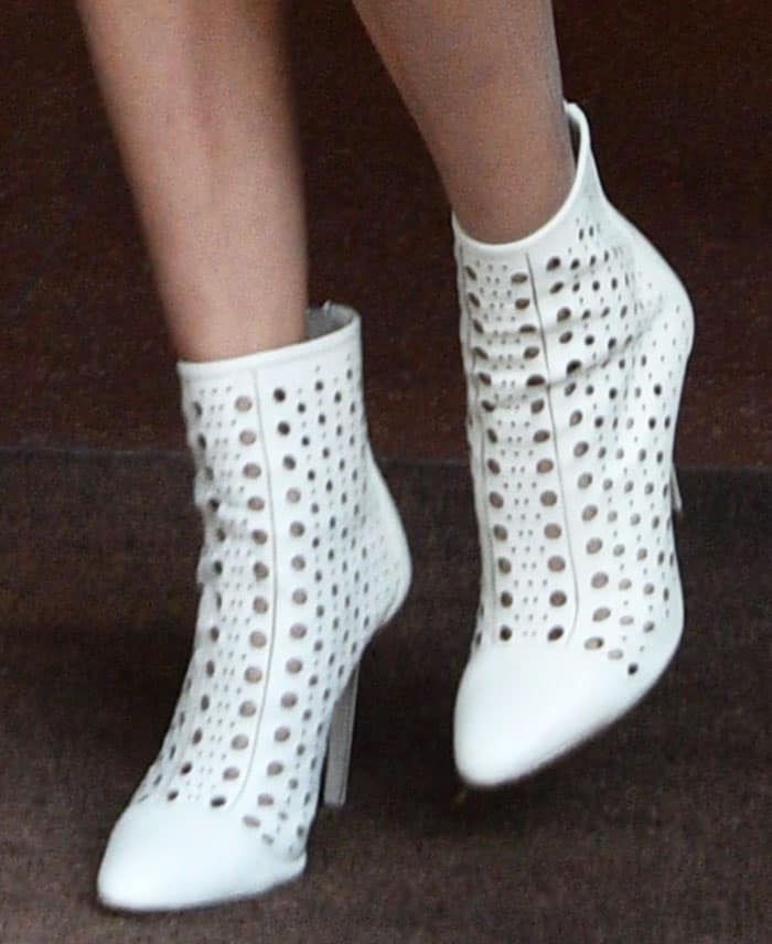 Bella Hadid steps out in chic white Tamara Mellon “Crossline” perforated ankle boots, featuring a lace-up front and stiletto heels