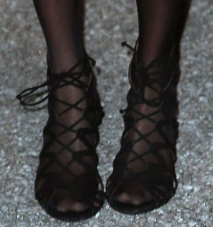 Pairing lace-up sandals with sheer black tights is a bold styling choice that adds texture and sophistication