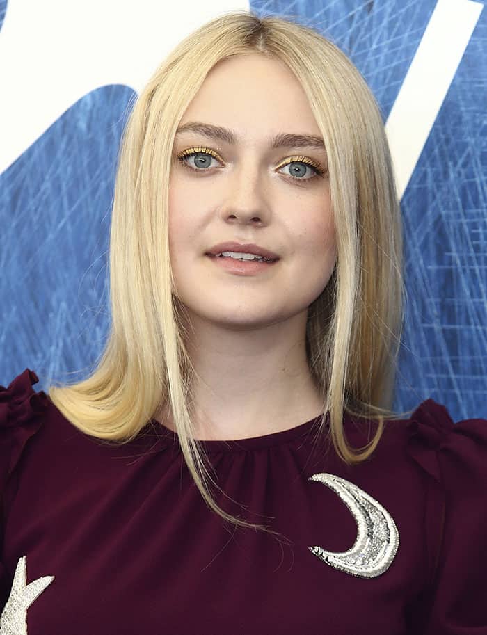 A close-up highlights Dakota’s beauty look, with soft gold eyeshadow and sleek, straightened blonde hair complementing the rich burgundy tone of her gown