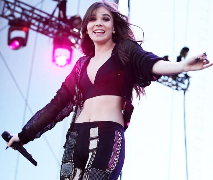 Hailee Steinfeld delivers an energetic performance at the daytime village, showcasing a bold stage outfit that includes a midriff-baring top, sheer layering, and intricately detailed pants