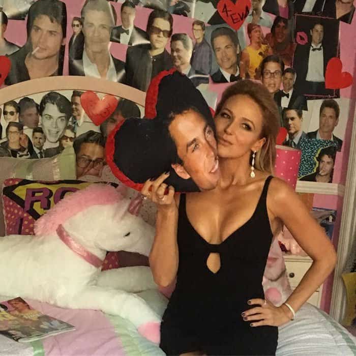 Jewel adds humor to the night by posing with a heart-shaped Rob Lowe pillow, proving her playful personality matches her polished red-carpet style