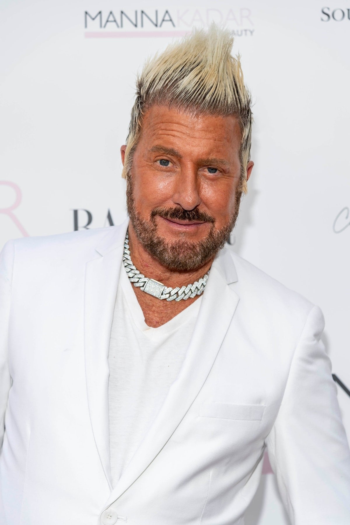 Photographer Jim Jordan—famous for discovering Taylor Hill at a Colorado ranch in 2011—steps out in a sharp white suit and dazzling diamond chain at the Manna Kadar Beauty event