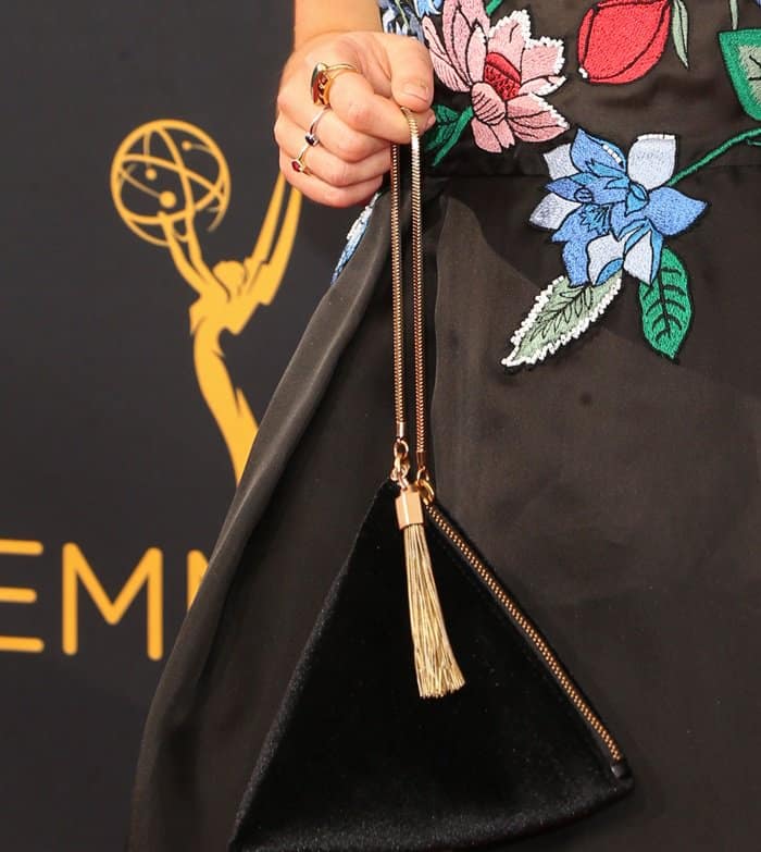 Maisie Williams adds a touch of glamour to the 2016 Emmy Awards with a Charles Keith triangle-shaped velvet purse, featuring a gold zipper and tassel detail—an affordable yet elegant red carpet statement