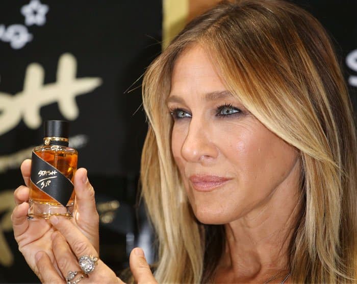 Sarah Jessica Parker holds up a bottle of her signature “Stash” fragrance during the launch event at Superdrug in Westfield London, highlighting the warm amber-toned scent she created as a more unisex departure from her earlier perfumes