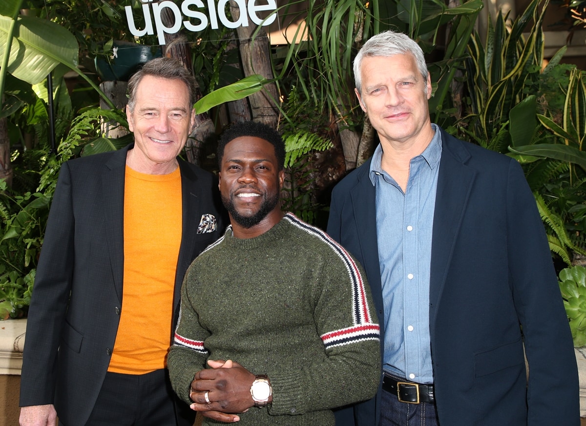 Kevin Hart stands out in his casual sweater as he poses with his much taller The Upside co-star Bryan Cranston and director Neil Burger, highlighting their noticeable height difference