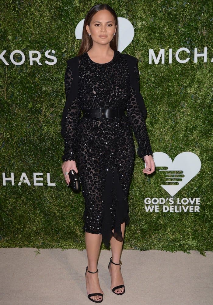 Chrissy Teigen radiates sleek sophistication in a black, crystal-embellished Michael Kors pencil dress cinched with a leather belt at the Golden Heart Awards