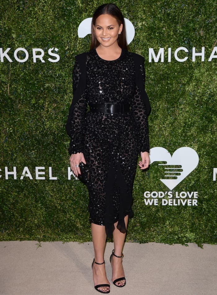 Facing the cameras, Teigen’s full-length look highlights the textural sparkle of her sequined Kors creation and her confident, red-carpet poise